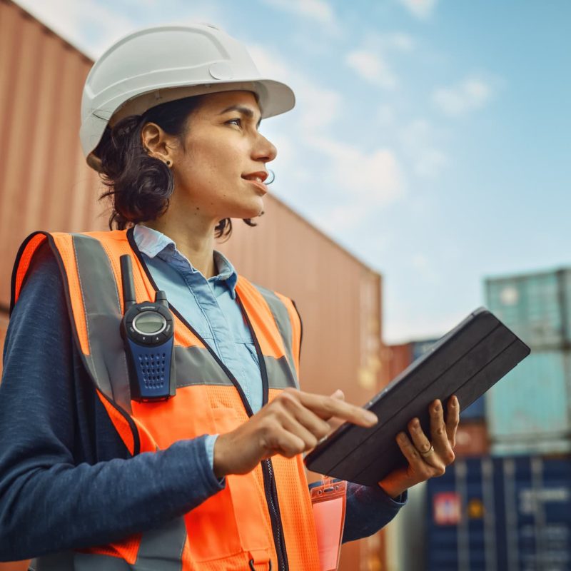 Vrouw met helm bij containers